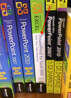 Books on a shelf, with PowerPivot shelved between many PowerPoint books.